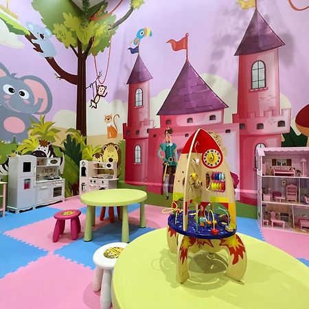 Evergreen Laurel Hotel - Taichung Luaran gambar The photo shows a colorful children's playroom designed with a whimsical theme. The walls are painted in bright colors and feature a cartoon-style mural of a pink castle with purple towers and a smiling cartoon elephant. The room is filled with playf