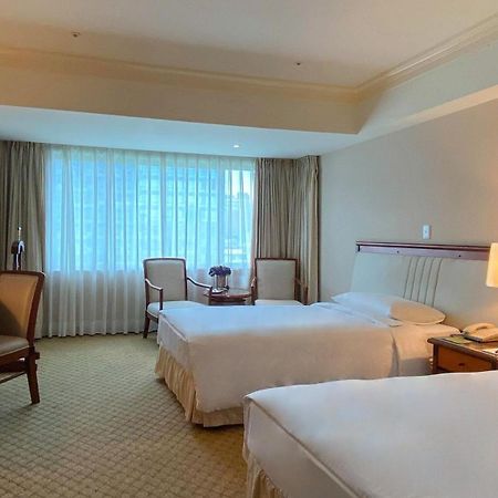 Evergreen Laurel Hotel - Taichung Luaran gambar The photo shows a hotel room featuring two single beds positioned near each other. There's a light-colored carpet on the floor and a large window with sheer curtains that allows natural light to fill the space. In the room, there are two chairs place