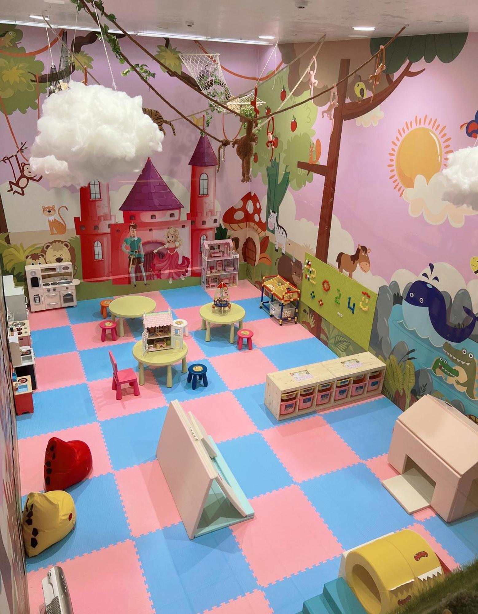 Evergreen Laurel Hotel - Taichung Luaran gambar The photo shows a colorful playroom designed for children. It features a vibrant mural with a fairytale castle, trees, and playful animals on the walls. The floor is covered with interlocking foam tiles in pink and blue, providing a soft play surface