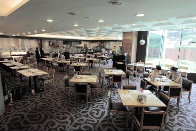Evergreen Laurel Hotel - Taichung Luaran gambar The photo shows a spacious restaurant or dining area with a modern interior design. There are several tables arranged throughout the room, some of which are set for dining while others appear to be empty. The decor includes a patterned carpet and lar