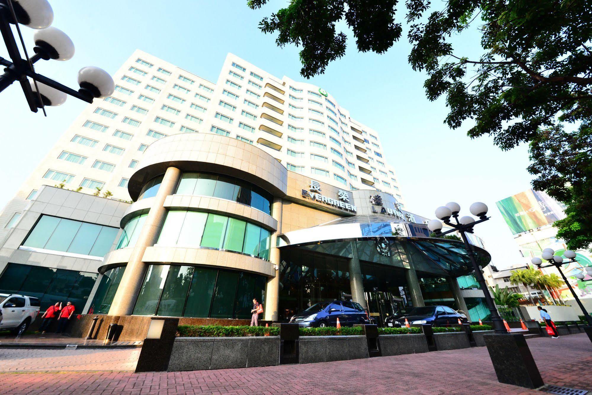 Evergreen Laurel Hotel - Taichung Luaran gambar The photo shows a modern multi-story building, which appears to be a hotel or commercial establishment. The structure has a rounded glass entrance with a distinctive architectural design, featuring large windows. The building is surrounded by greener