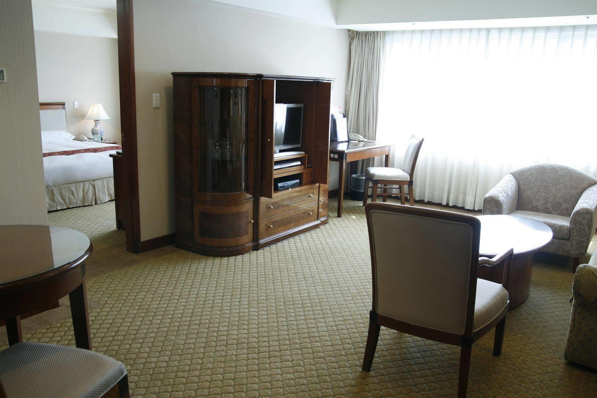 Evergreen Laurel Hotel - Taichung Luaran gambar The photo shows an interior of a hotel room suite. The space includes a living area with several pieces of furniture. There is a coffee table and chairs, creating a comfortable seating area. A wooden cabinet with a TV inside is situated against one w