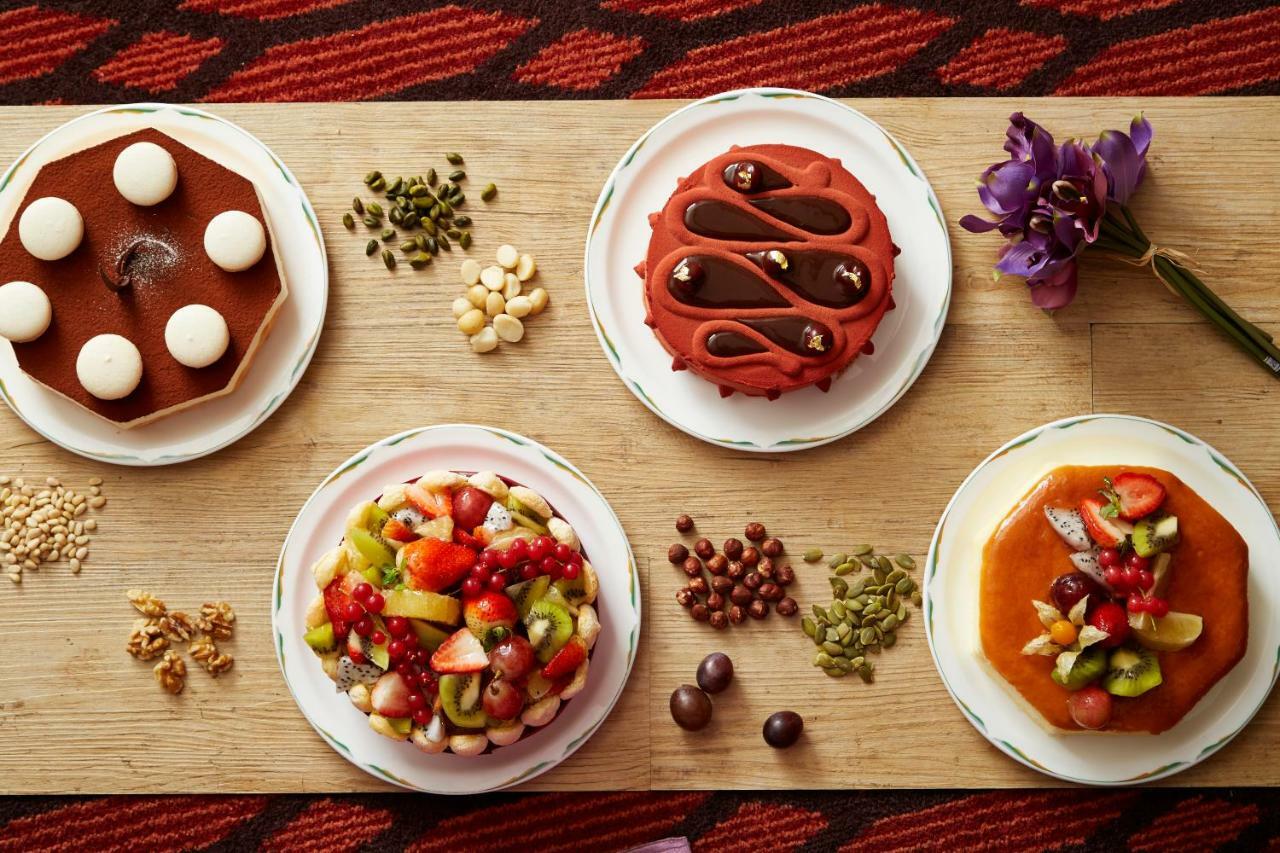 Evergreen Laurel Hotel - Taichung Luaran gambar The photo displays a variety of desserts arranged on small plates. There are three main cakes or tarts:

1. **Top Left Plate**: A round chocolate cake with a smooth surface and white decorations on top.
2. **Top Middle Plate**: Another cake, possibly