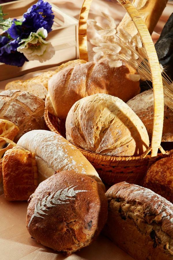 Evergreen Laurel Hotel - Taichung Luaran gambar The photo shows a variety of freshly baked bread arranged in a woven basket. There are different types of bread, including round loaves, baguettes, and crusty rolls, showcasing a range of colors and textures. Some loaves have distinctive patterns or 