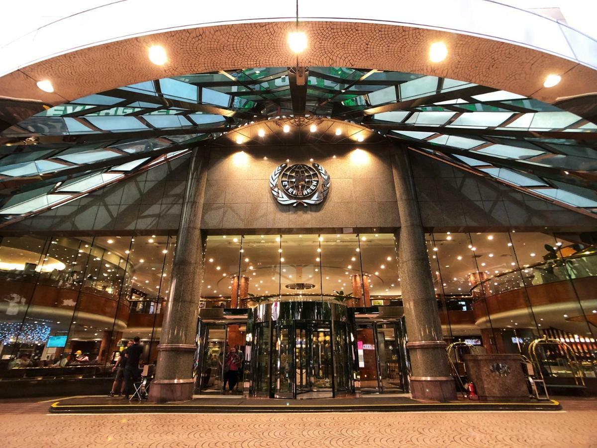 Evergreen Laurel Hotel - Taichung Luaran gambar The image shows the entrance of a modern building, likely a hotel or a luxury establishment. The entrance features a large revolving door surrounded by glass panels. Above the entrance, there is a prominent logo or emblem. The overall architectural d