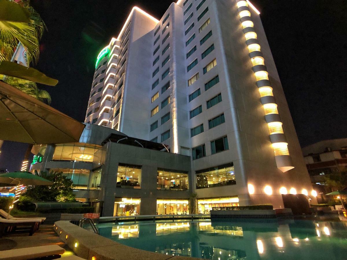 Evergreen Laurel Hotel - Taichung Luaran gambar The photo shows a tall hotel building at night, illuminated by lights. The architecture appears modern, with several floors and large windows. In the foreground, there is a swimming pool that reflects the lights from the building, creating a serene a