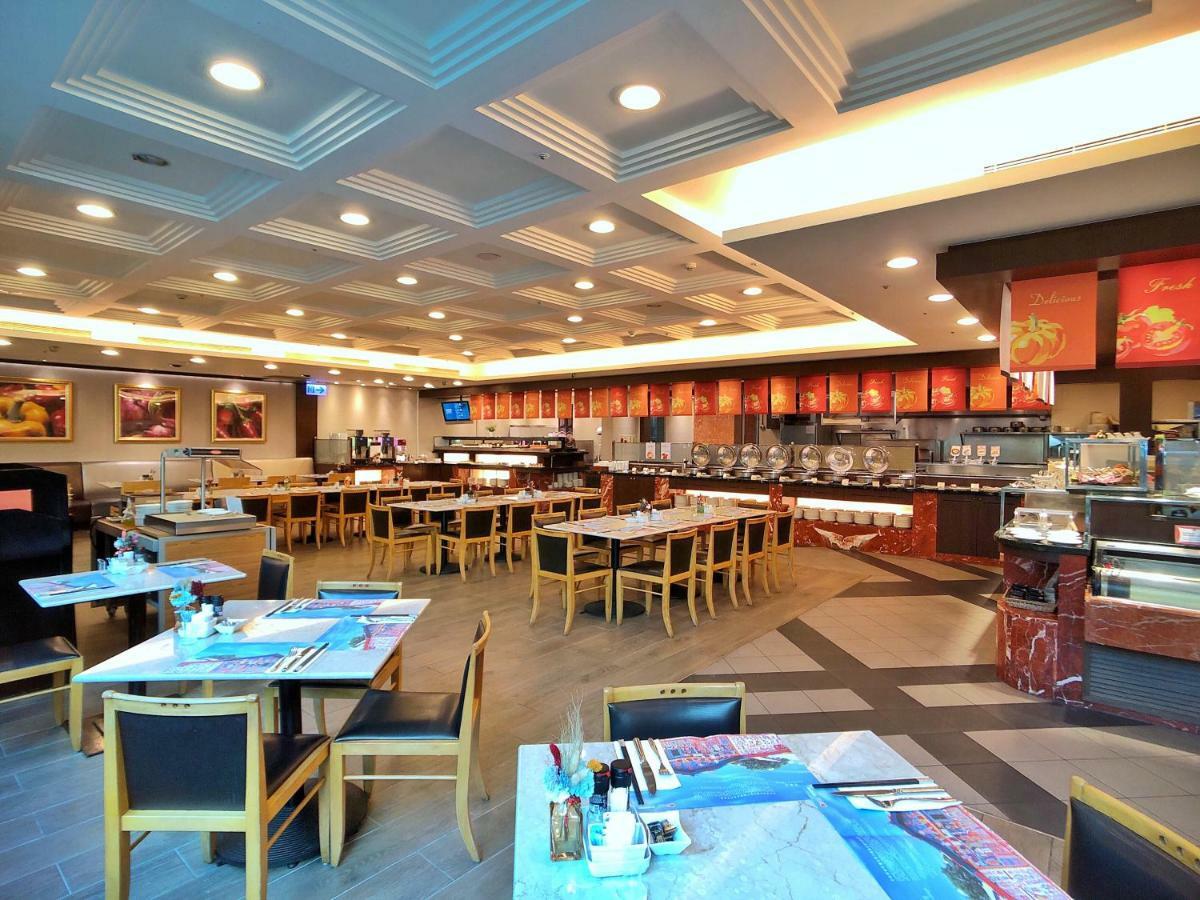 Evergreen Laurel Hotel - Taichung Luaran gambar The photo shows the interior of a restaurant. The dining area features several tables with chairs arranged neatly. The flooring has a contemporary design, and the ceiling is structured with a coffered pattern. There is a buffet area along one wall wi