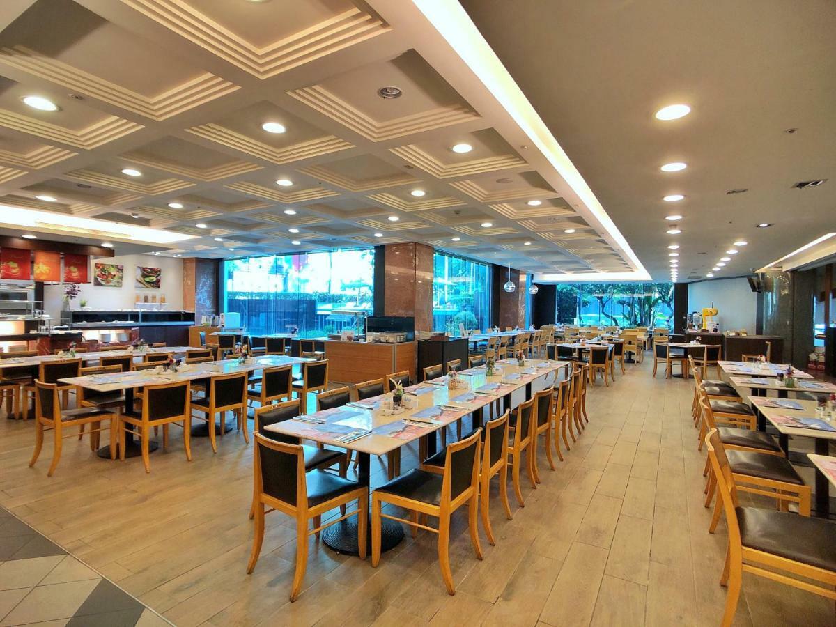 Evergreen Laurel Hotel - Taichung Luaran gambar The photo shows the interior of a restaurant. It features a spacious dining area with several wooden tables and chairs arranged in rows. The floor has a light wood finish, complementing the stylish design. The ceiling is decorated with a modern patte