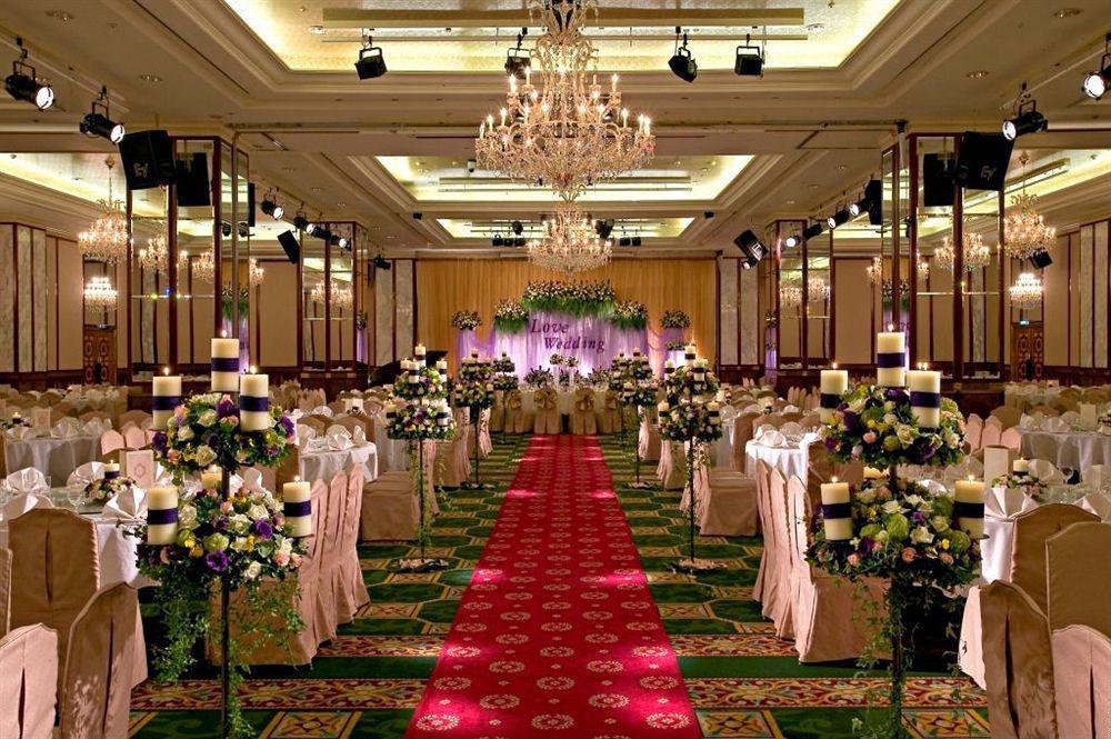 Evergreen Laurel Hotel - Taichung Luaran gambar The photo shows an elegantly decorated banquet hall set up for a wedding or formal event. The center aisle is lined with rows of elegantly draped chairs and features a bright red carpet. On either side of the aisle, there are beautifully arranged flo